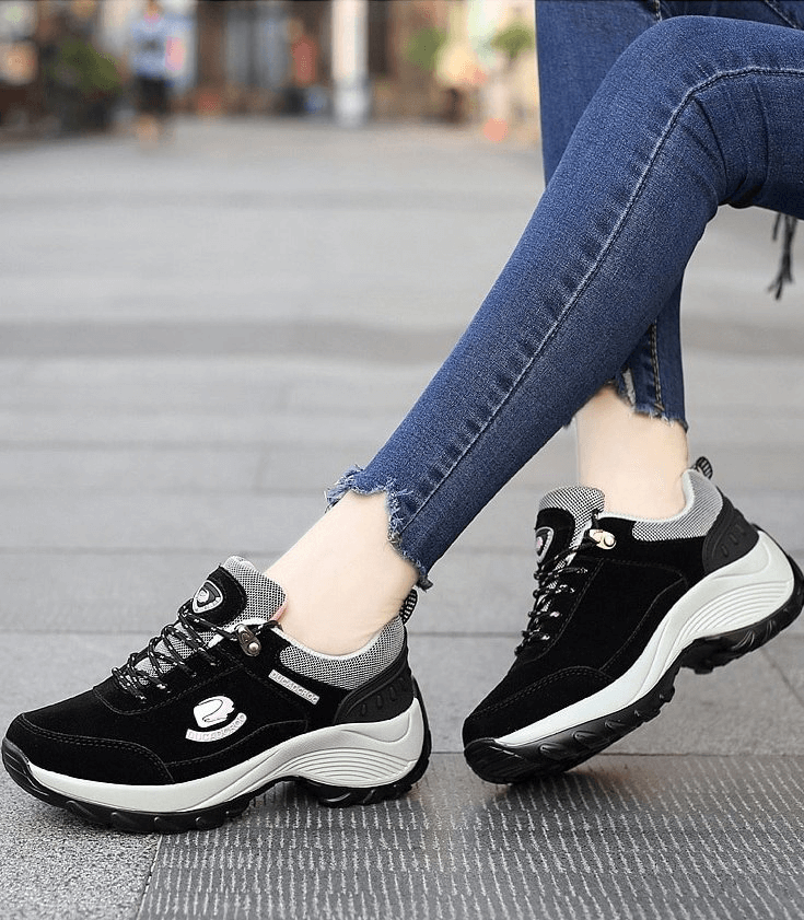 Woman wearing sports stylish black suede sneakers with lace-up design, featuring lightweight animal print for comfort and stability.